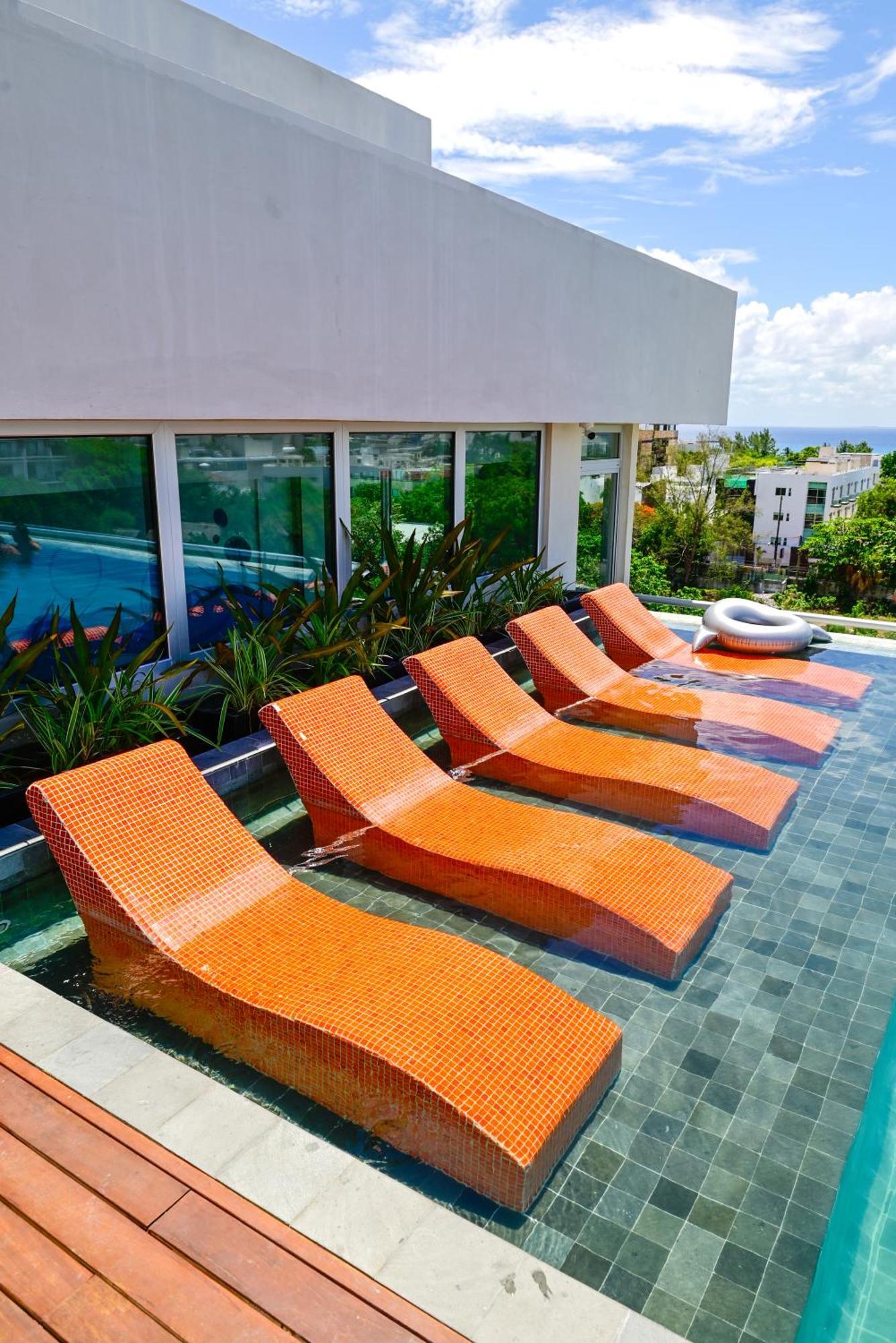 Aloft Playa Del Carmen Hotell Eksteriør bilde Sunbathing chairs at a pool